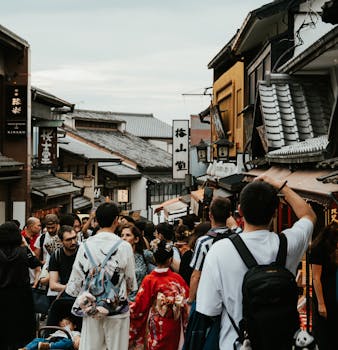 Crowded street scene in Kyoto with traditional architecture and people in kimonos.