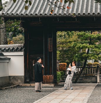 Two people in traditional Japanese attire near a historic gate in Kyoto, Japan.