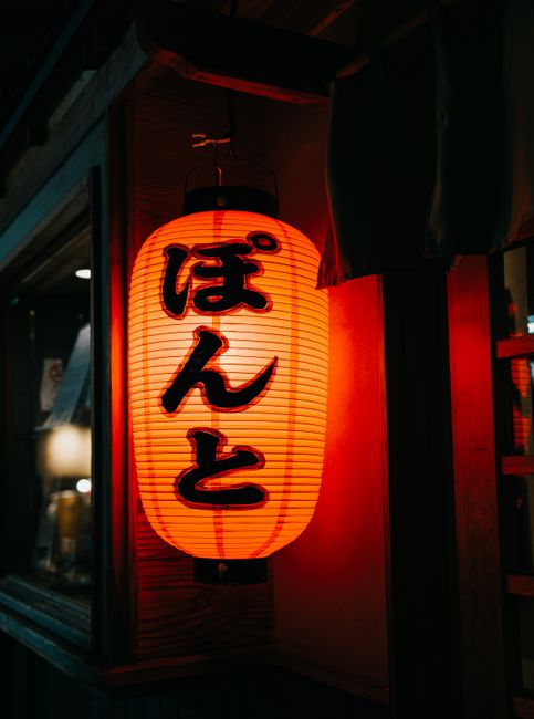 Illuminated Japanese lantern hanging outside a building, creating a warm, cultural ambiance.