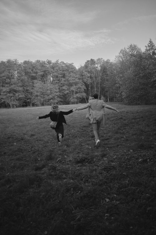 Free A couple holding hands and running through a tranquil meadow. Perfect moment of freedom. Stock Photo
