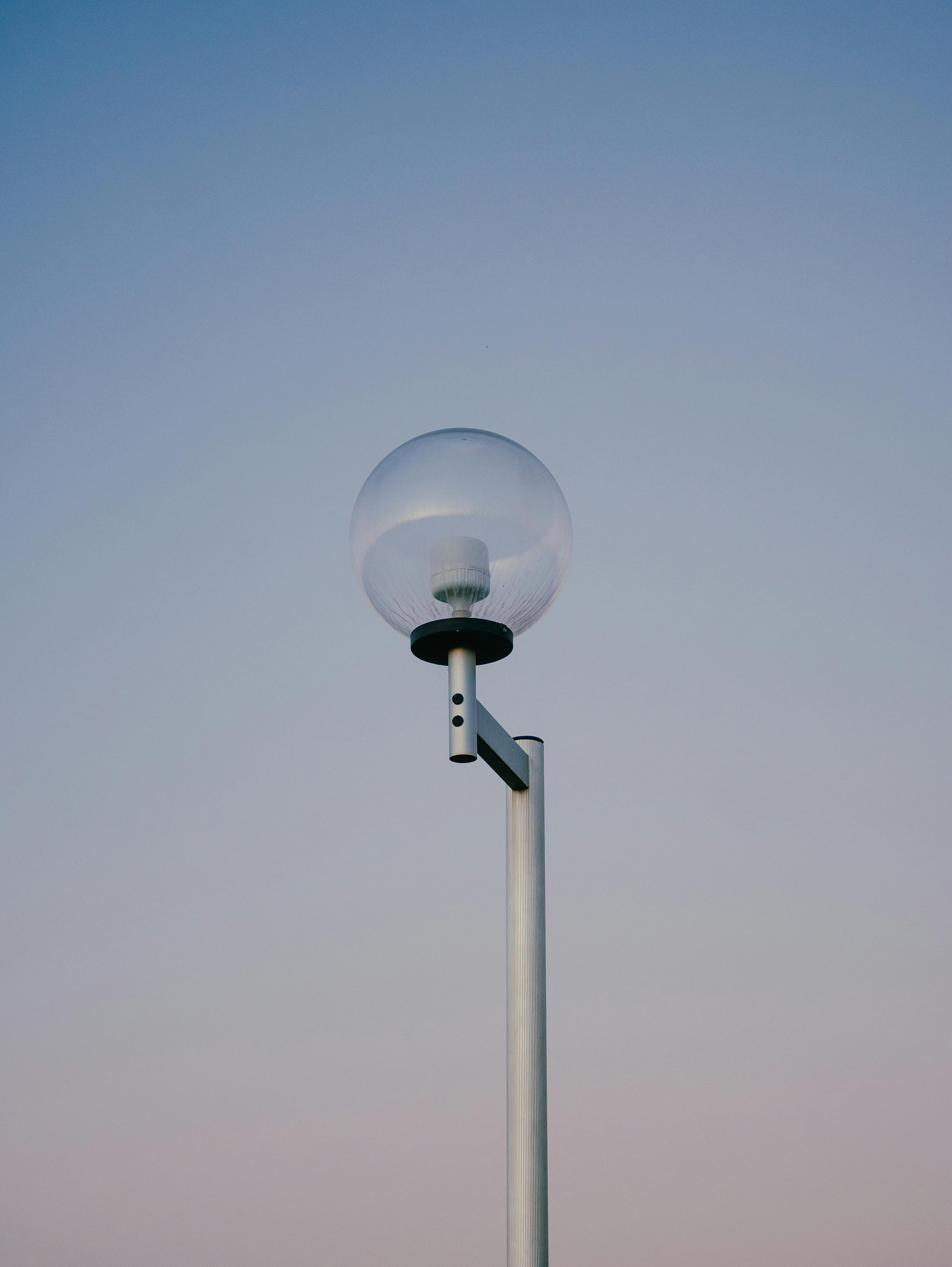A single street lamp stands against a clear twilight blue sky, creating a minimalist scene.
