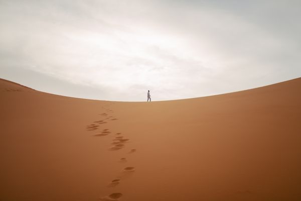 Lone hiker on Merzouga dunes at dusk