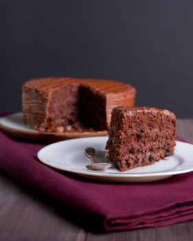 Savor the rich taste of a chocolate cake slice on a white plate with a fork.