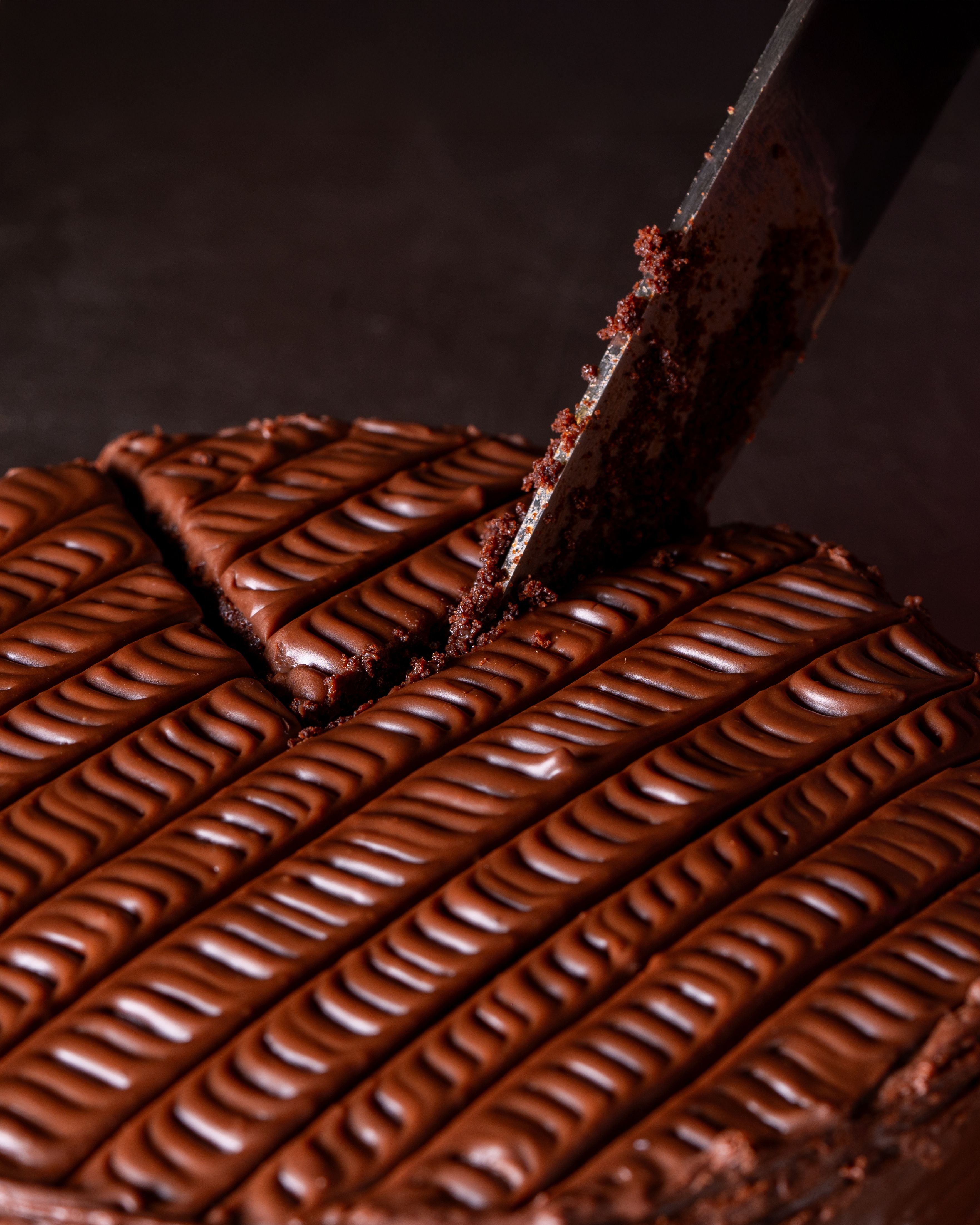 Delicious chocolate cake with intricate frosting being sliced. Perfect dessert imagery.