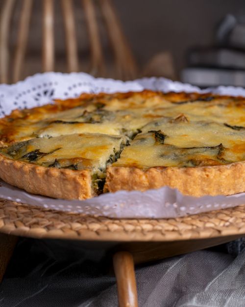 Free Homemade spinach and cheese quiche on a wicker plate, perfect for brunch. Stock Photo