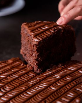 Close-up of a rich chocolate cake slice being lifted from a tray with elegant swirls