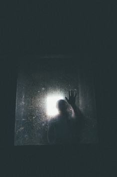 剪影：灯光下，一个人将手按在雾玻璃上
