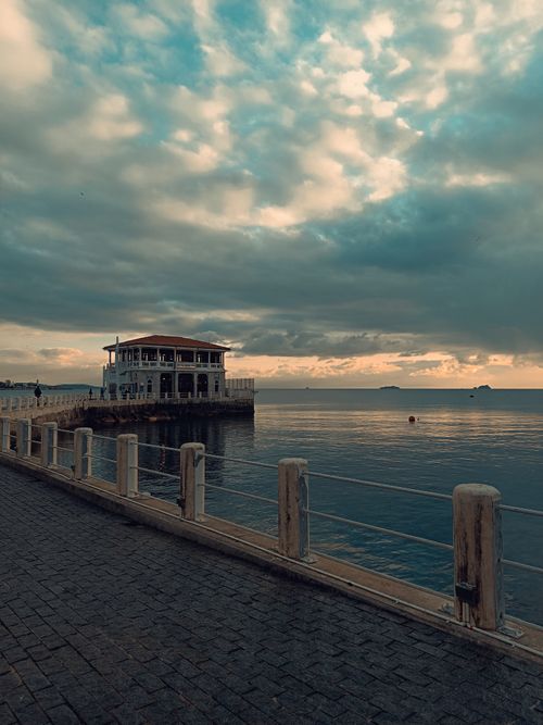 Free Serene view of a historic building on Bosphorus coastline with dramatic clouds at dusk. Stock Photo