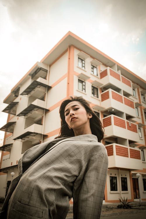 Woman Wearing Gray Coat Across White and Orange Building