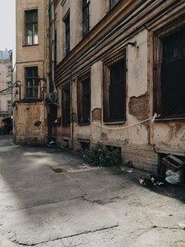 一条阳光明媚的小巷，紧邻一座废弃建筑，展现出城市的衰败与年久失修