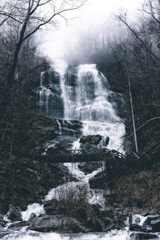 A serene misty waterfall in winter with surrounding forest, evoking calm and tranquility.