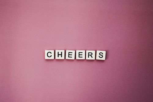 Free Scrabble-style tiles spelling 'Cheers' on a pink background for celebrations. Stock Photo