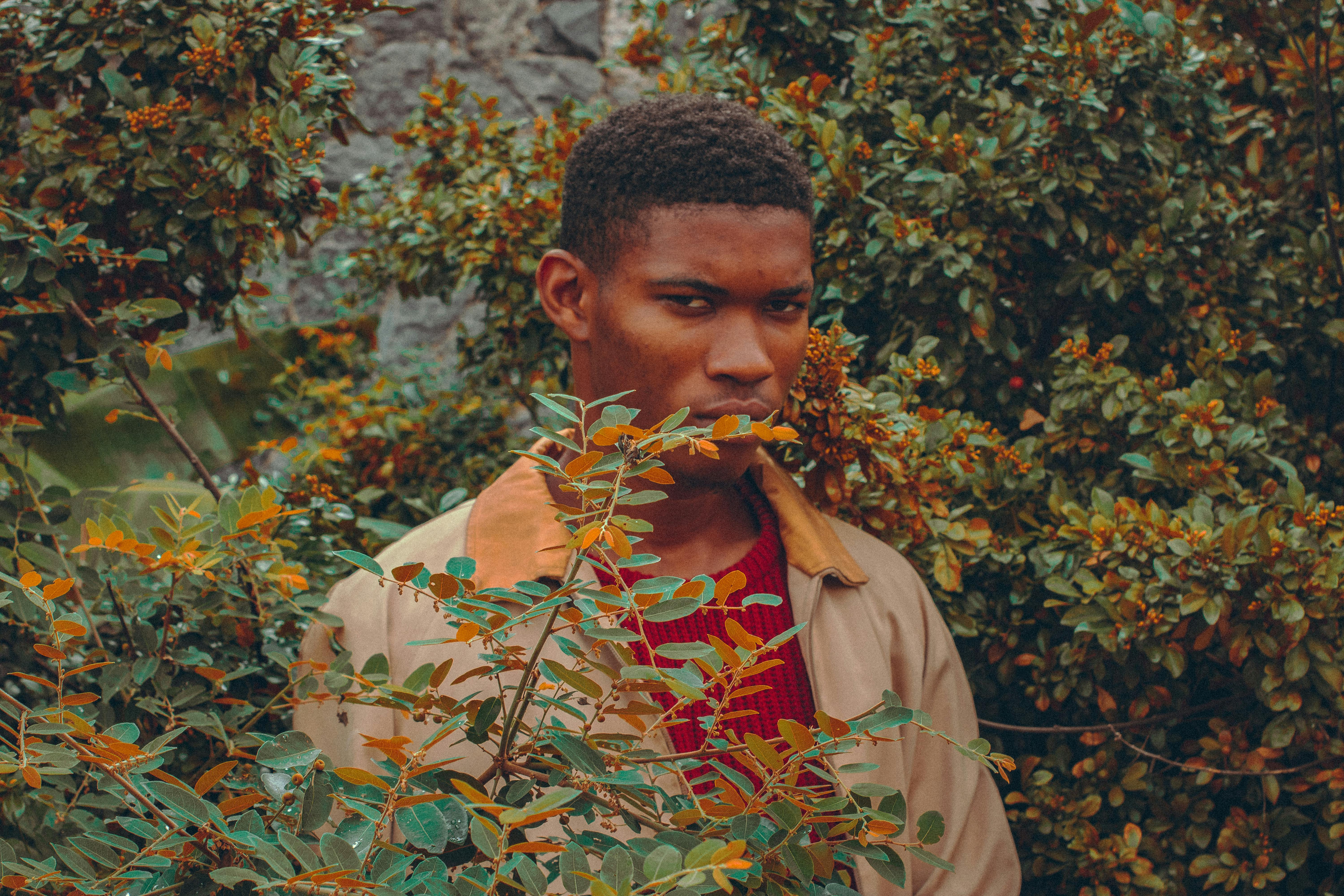 Portrait of a young man among autumn foliage displaying a thoughtful expression.