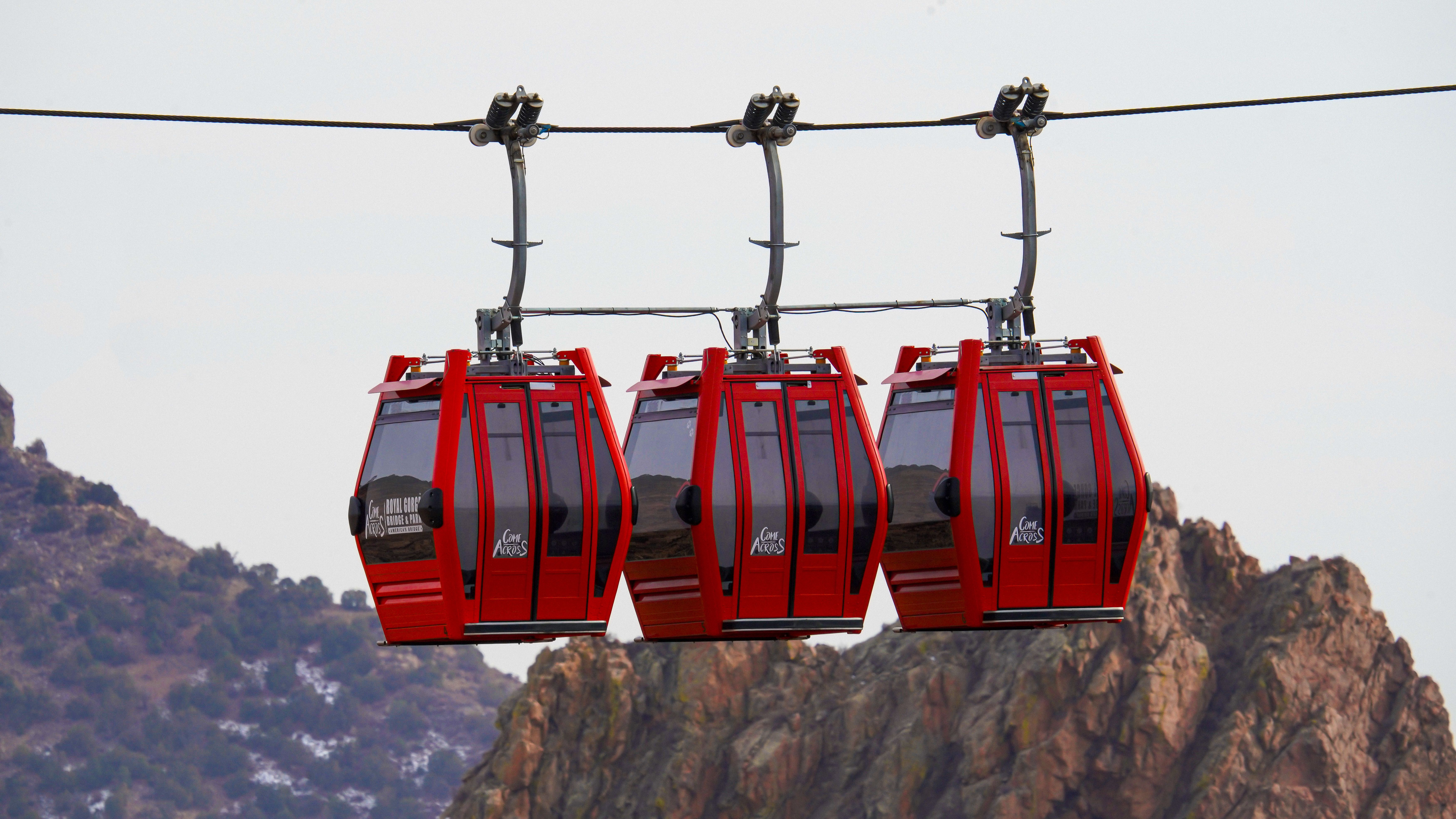 Vibrant red cable cars suspended against a mountainous landscape.