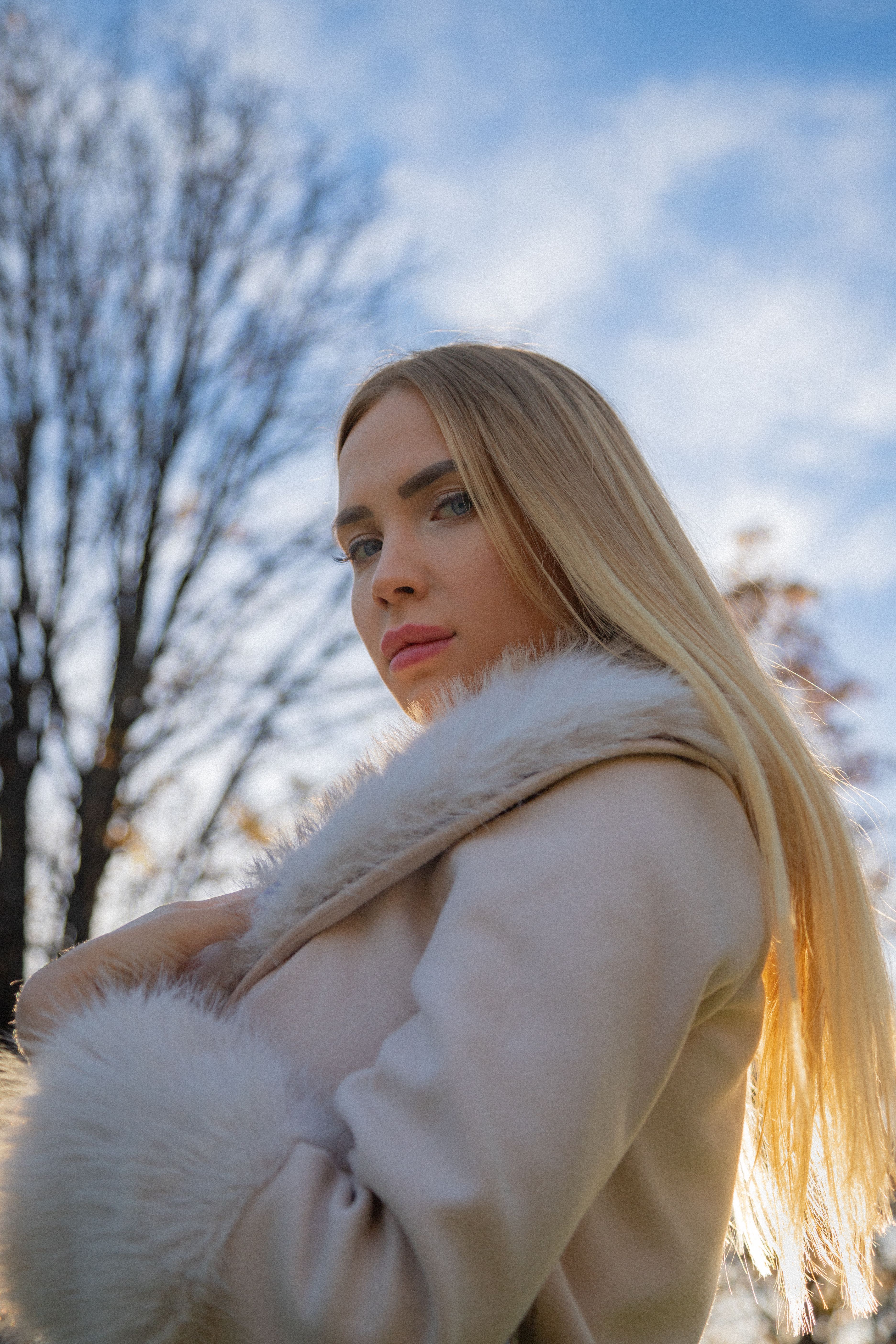 Blonde woman with blue eyes in a fur coat, enjoying a sunny day in Munich, Germany.