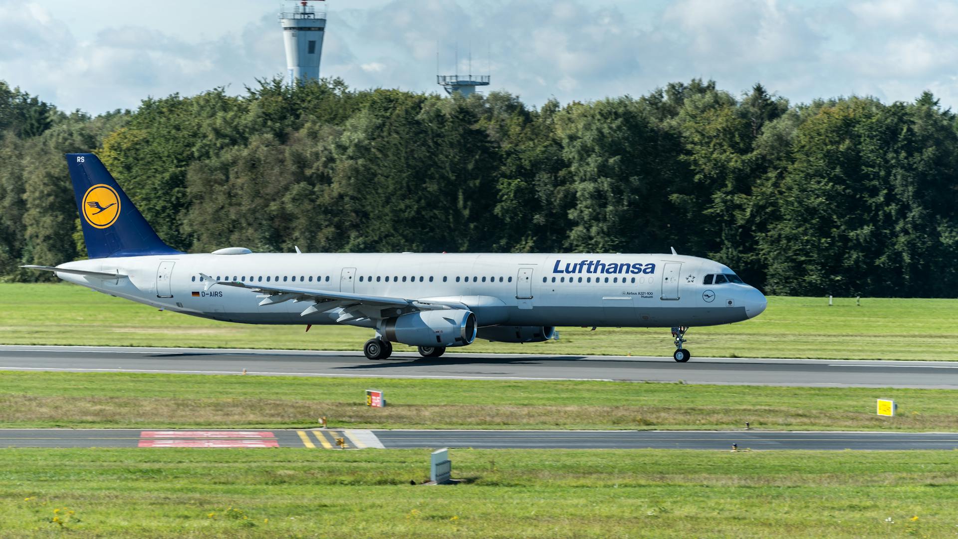 A Lufthansa Airbus A320 taxiing on the runway at Hamburg Airport on a clear day.