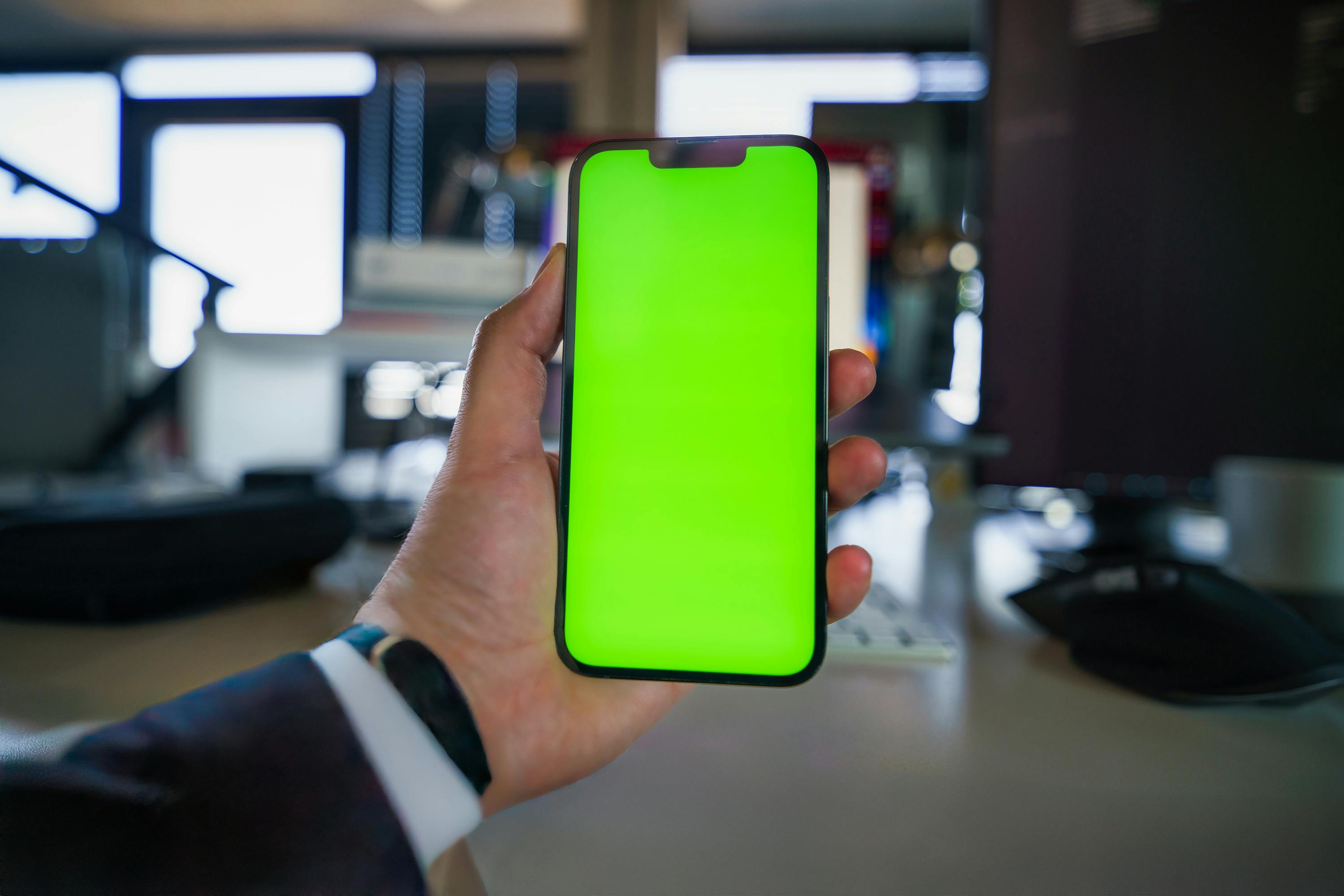 businessman hand holding smartphone green screen mockup office space interior