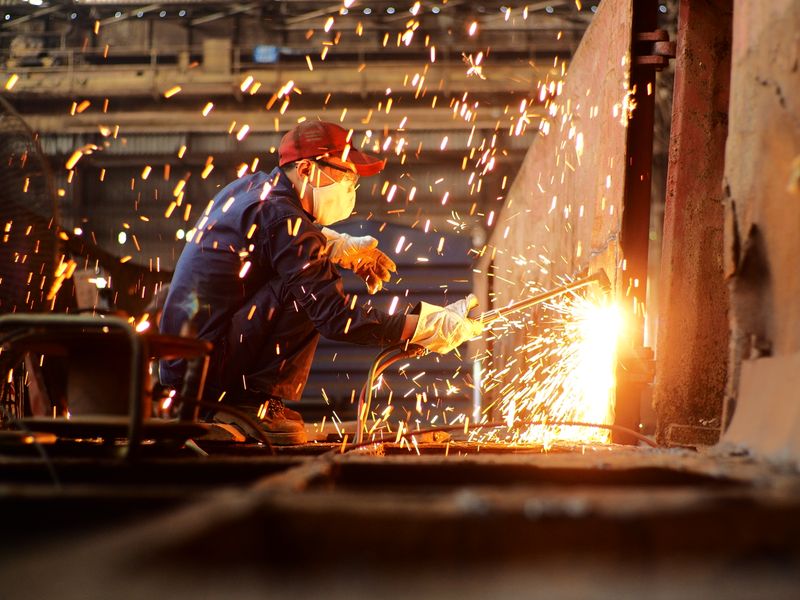 Industrial welder working in factory with sparks — precision fabrication quality