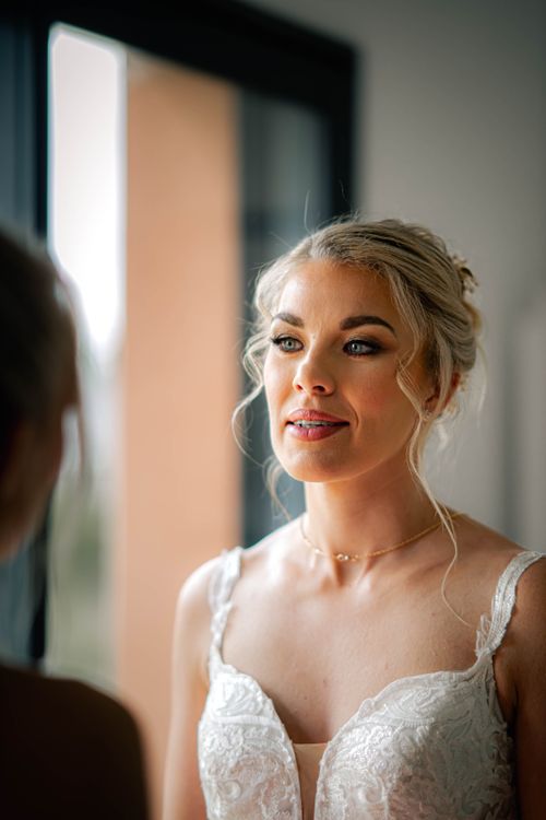 Free A bride in a white gown preparing for her wedding day indoors, bathed in natural light. Stock Photo