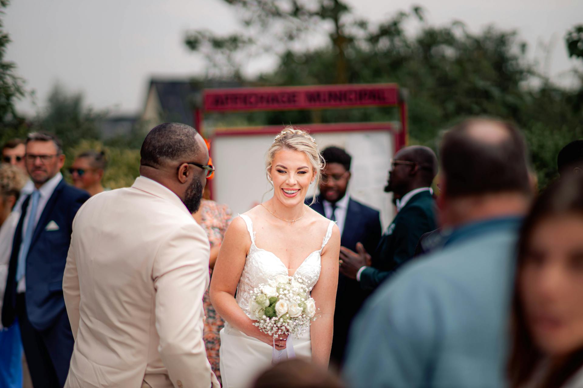 Bride smiling as she interacts with guests at an outdoor wedding ceremony.