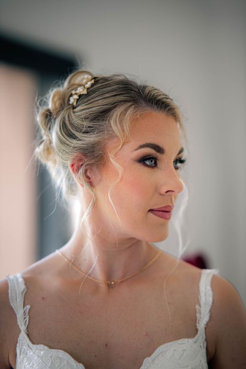 Free Beautiful blonde bride in white dress with elegant updo gazing sideways. Stock Photo