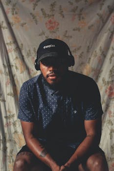 一位戴着耳机和帽子、留着胡须的时尚男子在室内摆出严肃的姿势