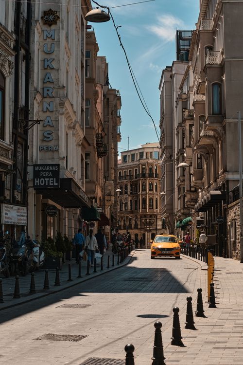 Free Explore the vibrant streets of central Istanbul featuring a traditional yellow taxi and bustling architecture. Stock Photo