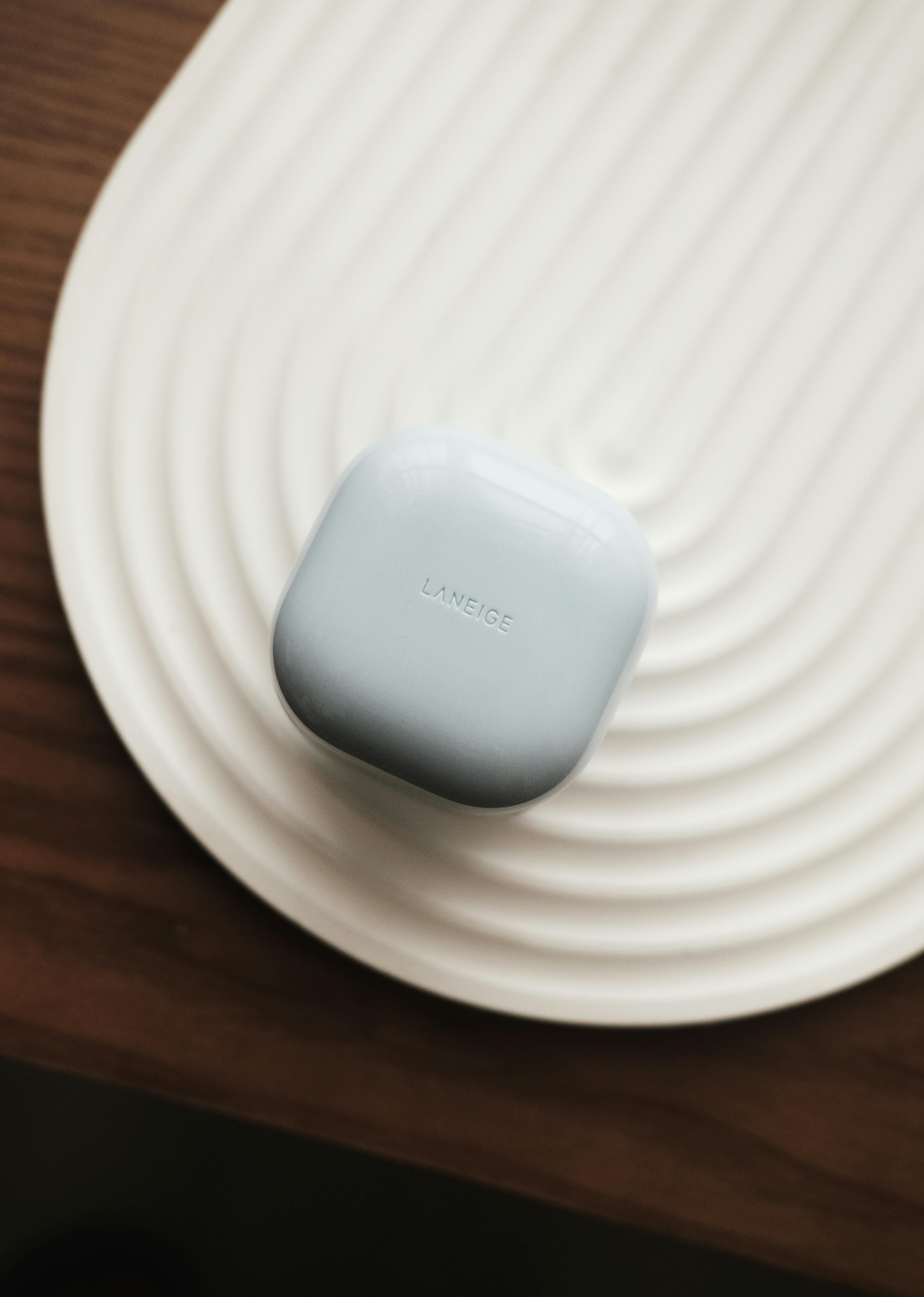 Simple and elegant display of Laneige beauty product on textured white surface.
