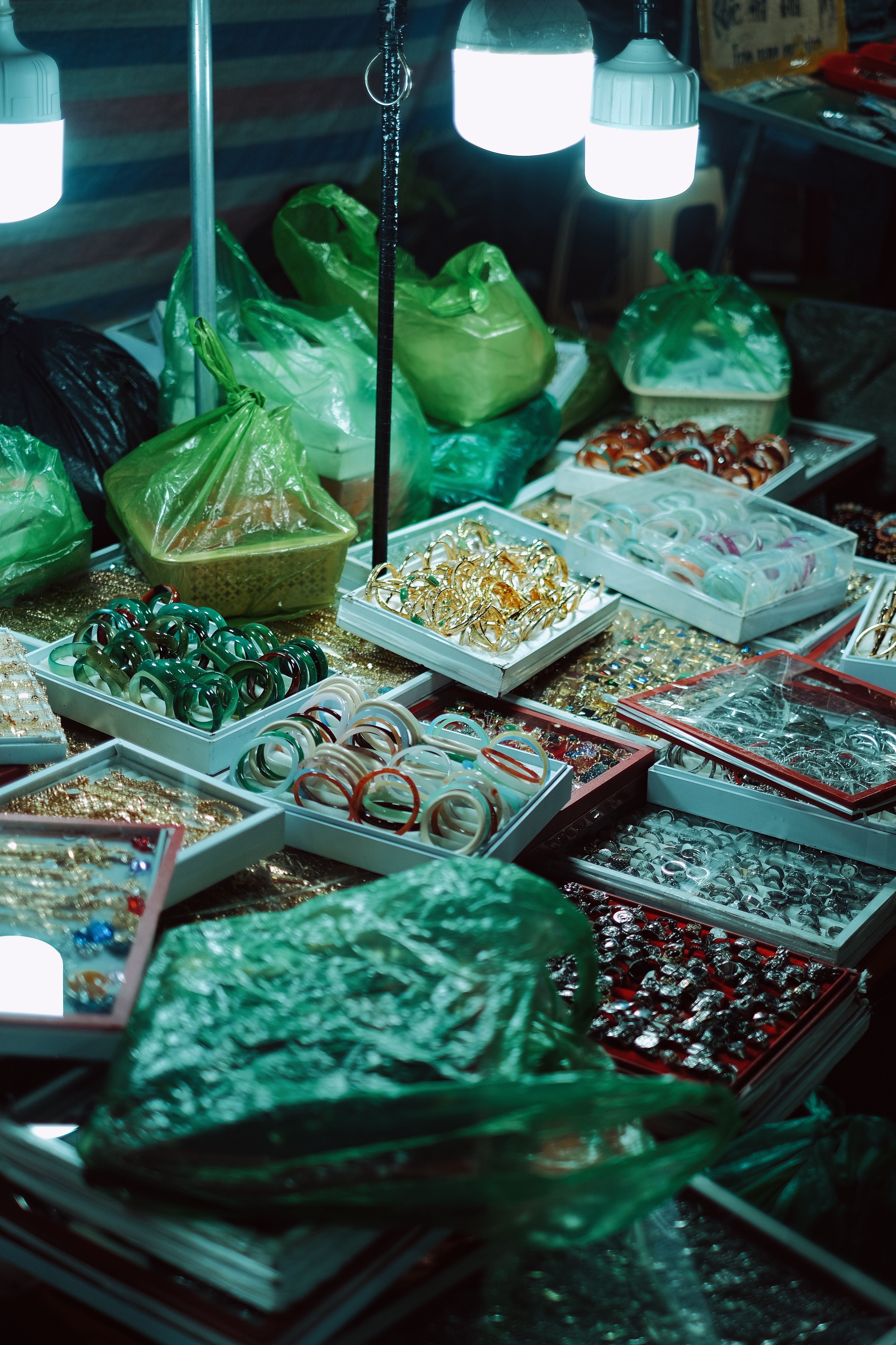 Colorful collection of jewelry at a night market, illuminated by overhead lights.