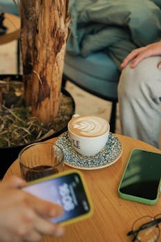 Cozy coffee break with latte art among friends' smartphones in a cafe setting.
