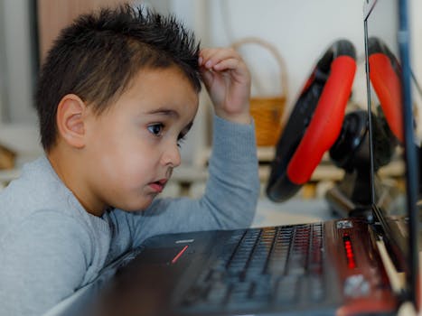 Child intensely focused on computer gaming with racing wheel accessory at home.
