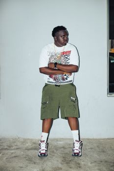 Man in a bold graphic t-shirt, shorts, and sneakers in an urban setting.