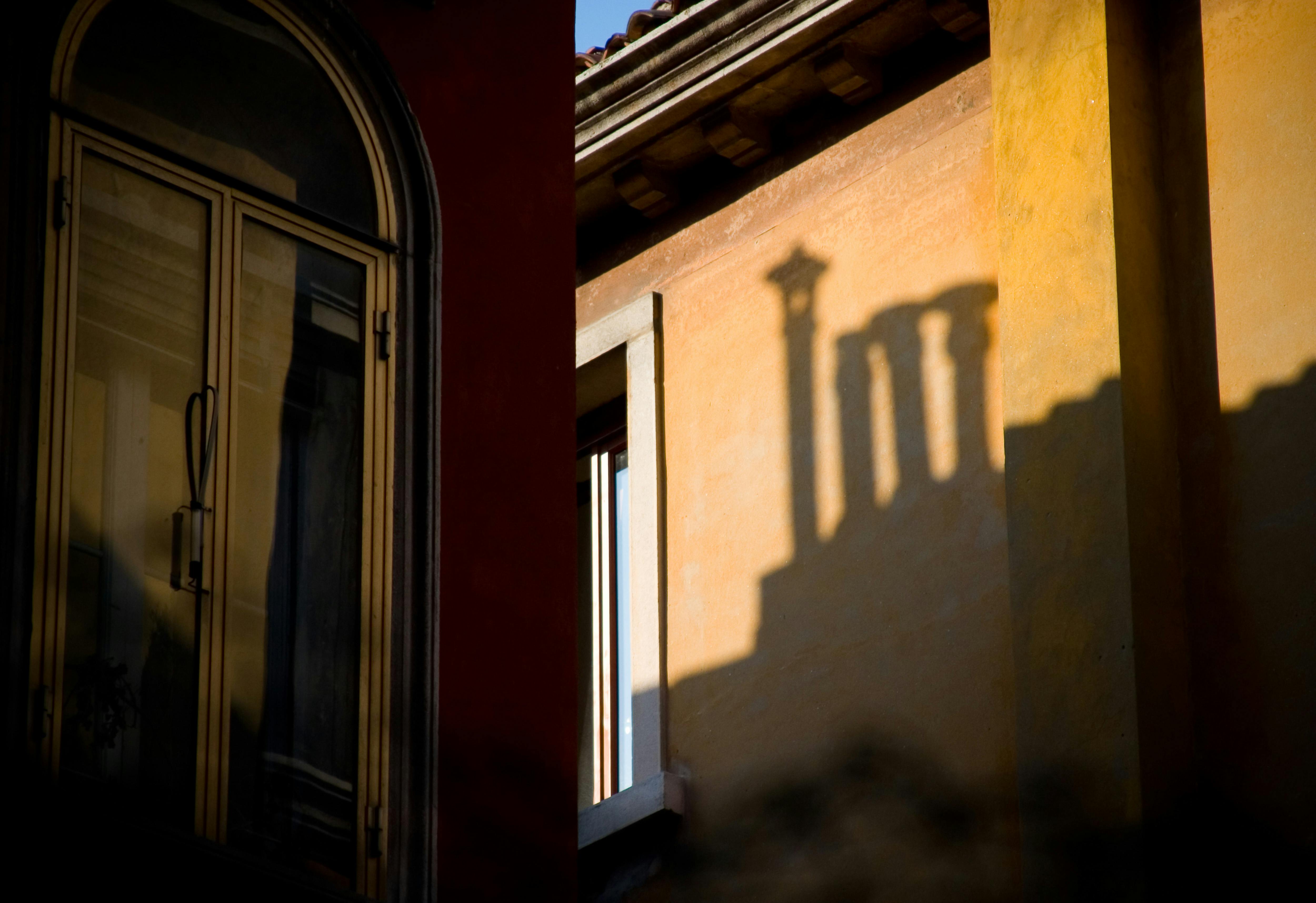 A striking shadow of classical architecture cast on an Italian building, showcasing evening light ambiance.