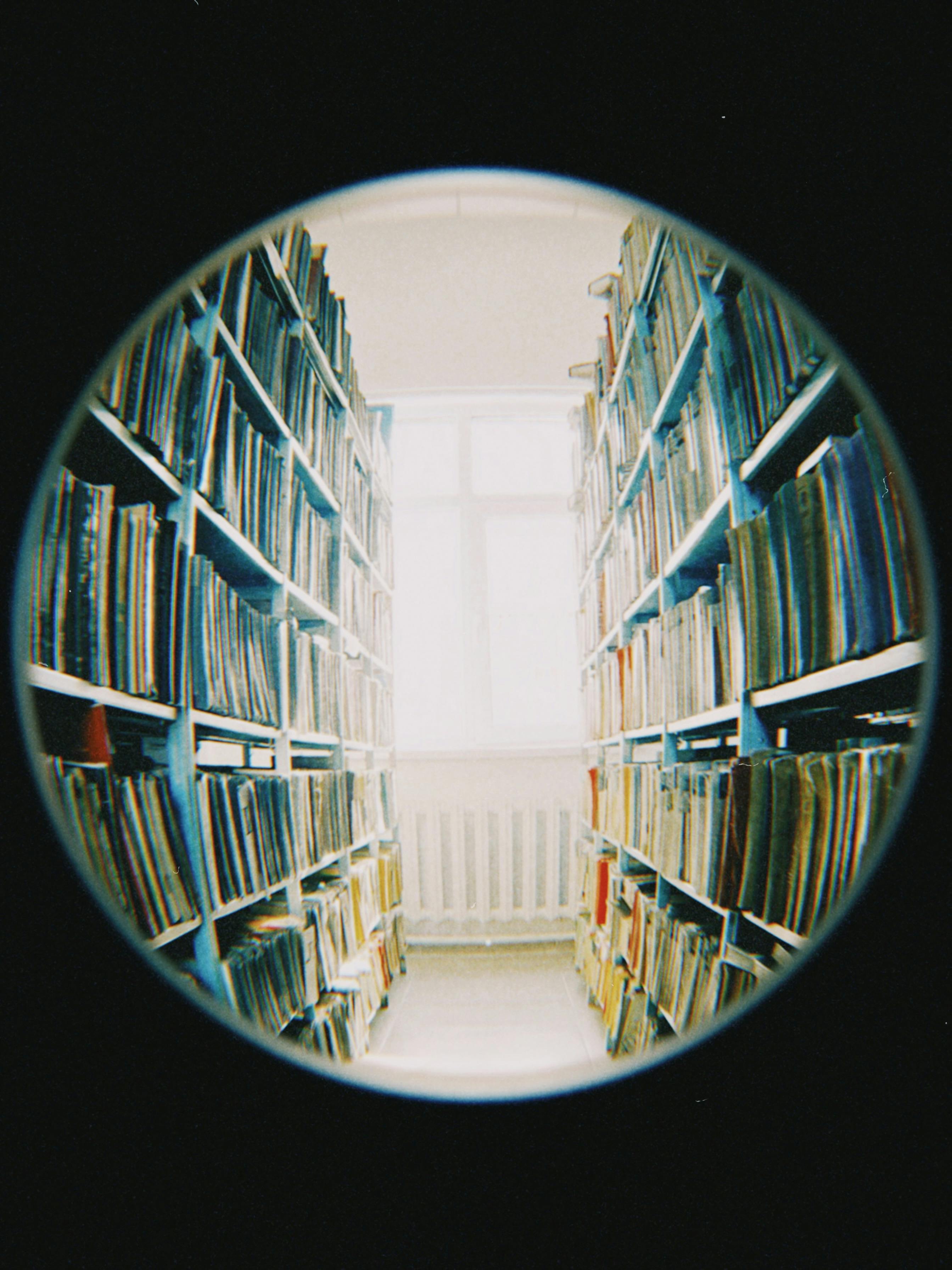 Unique fisheye view of a library aisle in Almaty, showcasing rows of bookshelves under natural daylight.