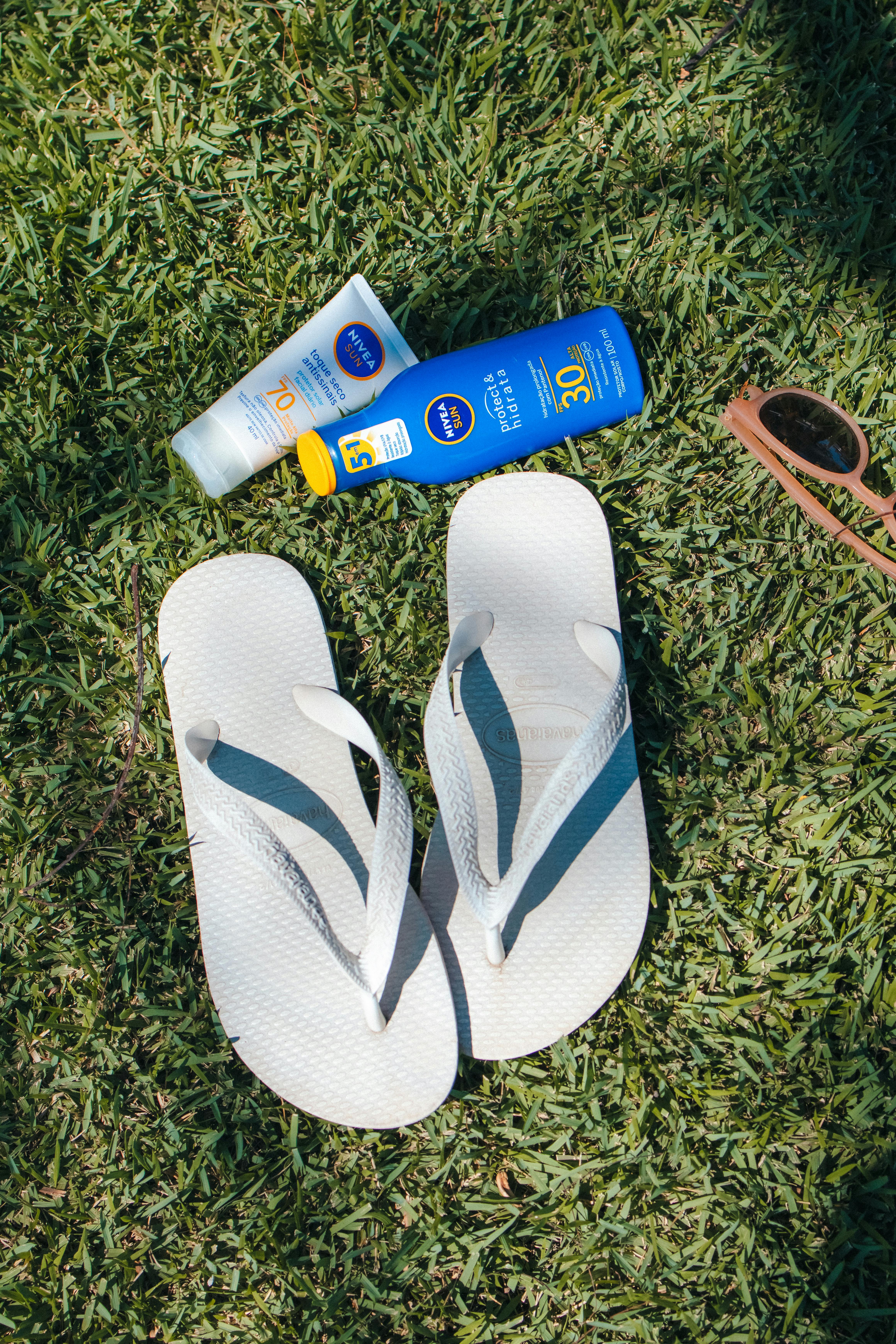 Flip-flops, sunblock, and sunglasses on grass evoke summertime leisure in Brazil.
