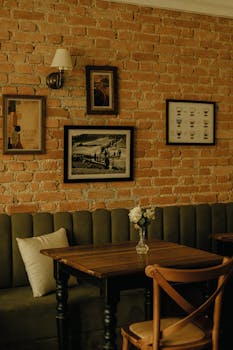 Warm cafe corner with rustic brick walls, wooden table, and framed art.