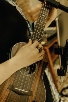 A woman softly strums a ukulele indoors, creating a cozy and artistic mood.
