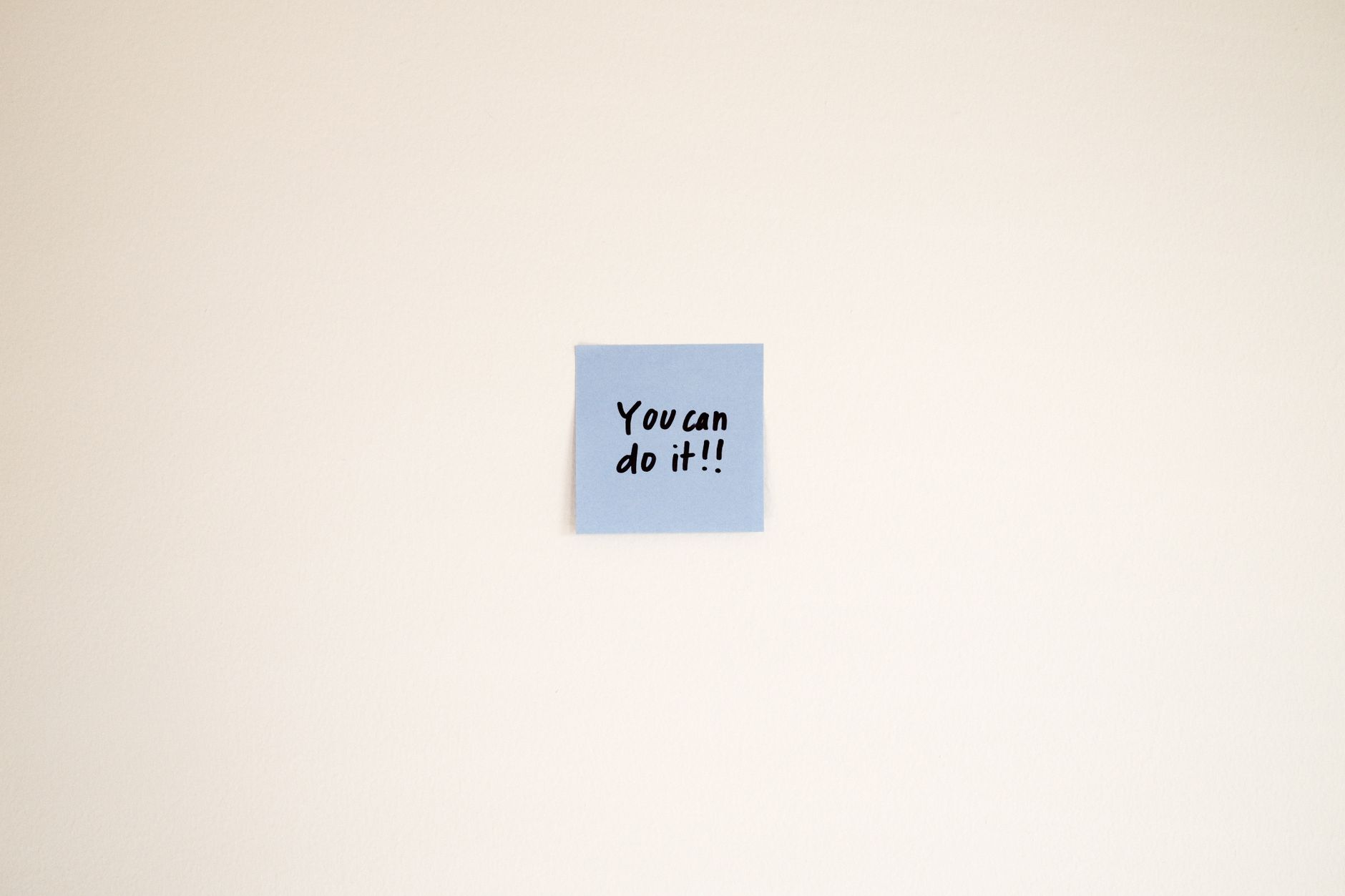 A motivational message on a blue Post-it note reads 'You can do it!' on a cream wall. — photo by Airam Dato-on