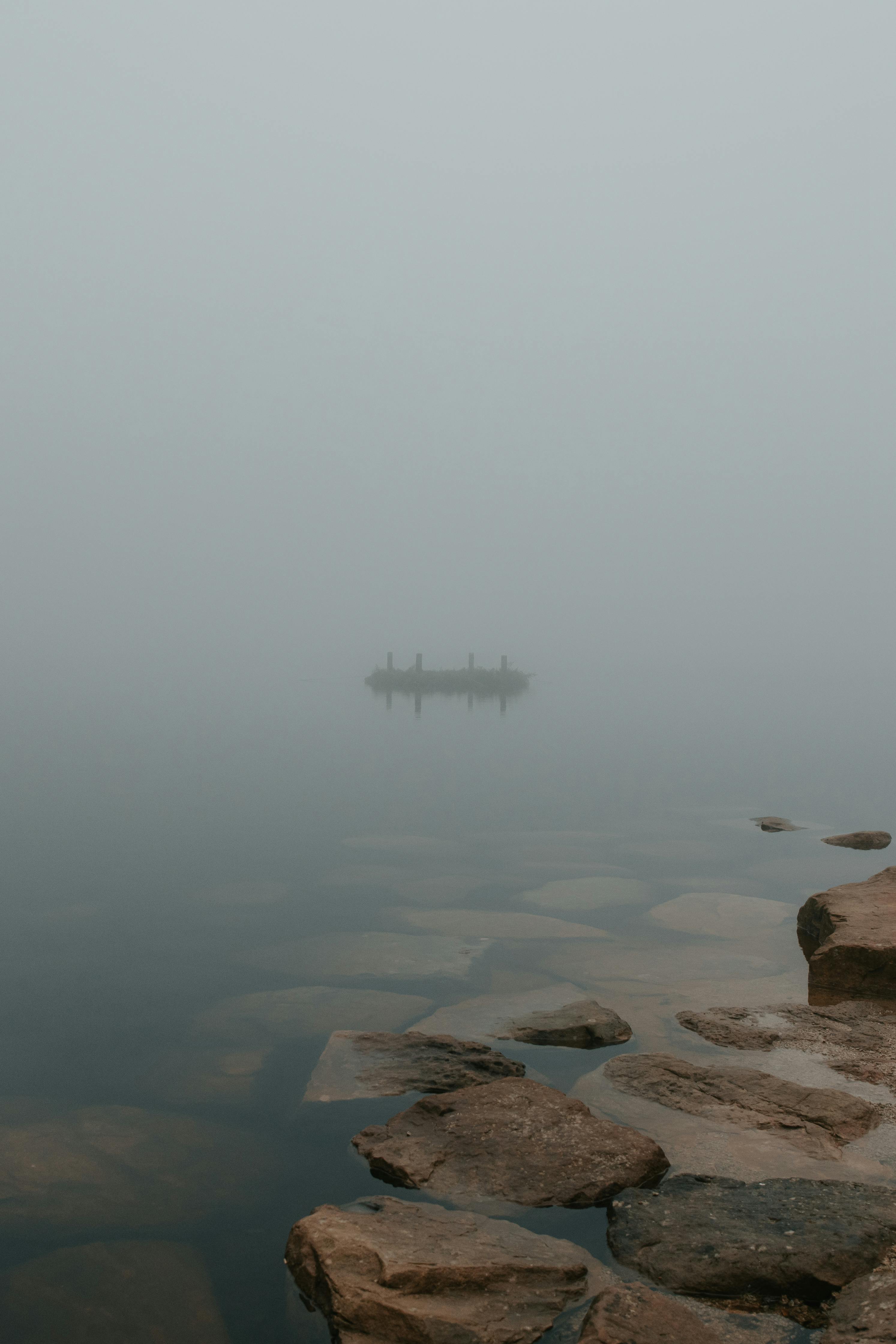 misty lake with rocks in moody atmosphere