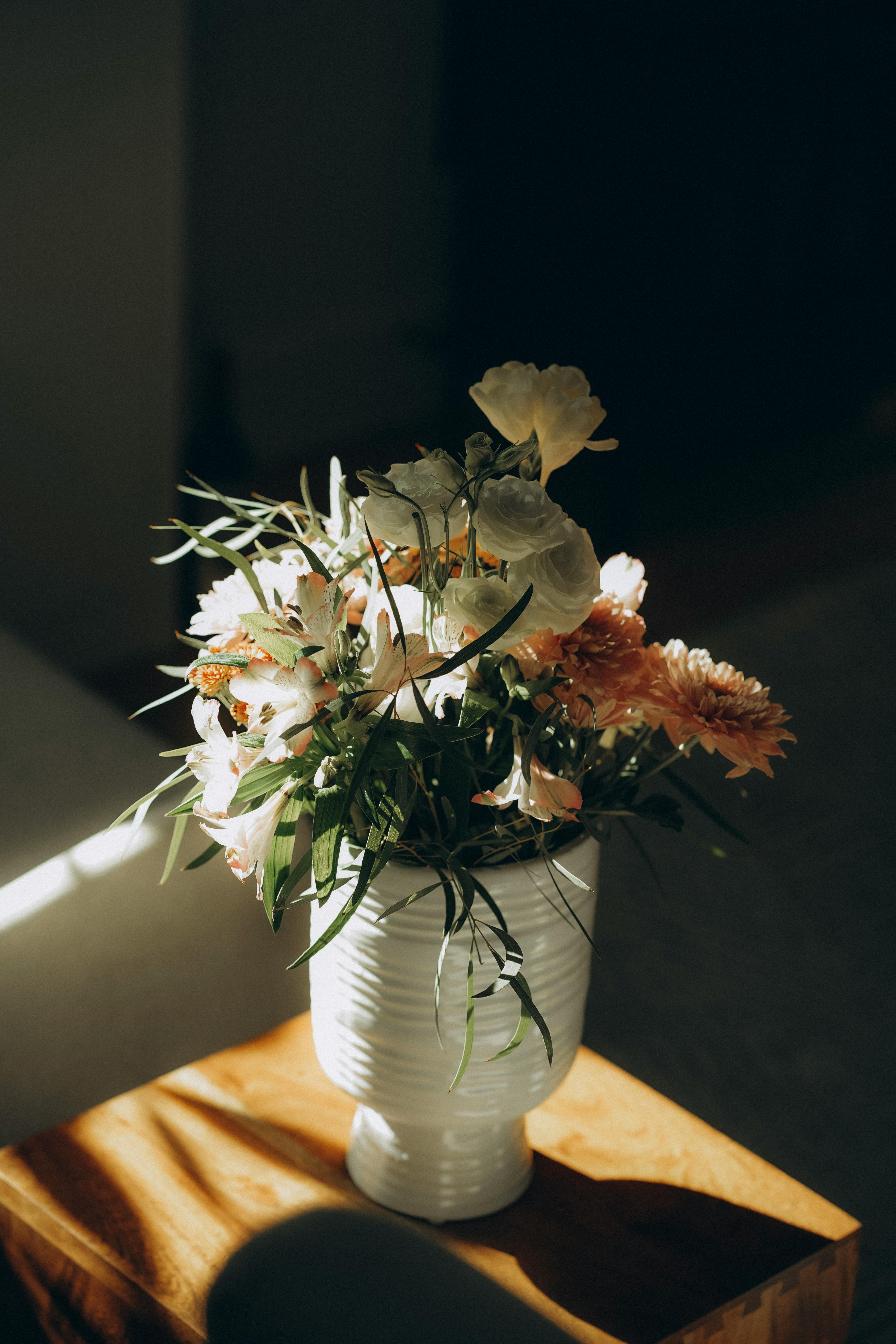 A serene floral arrangement in a ceramic vase, beautifully lit by natural sunlight.