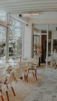 Charming indoor cafe with cozy seating and snowy outdoor view. Ideal for winter ambiance.