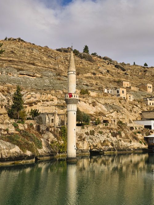 Free Sunken minaret in a scenic, rocky hillside by calm waters, showcasing history and nature. Stock Photo