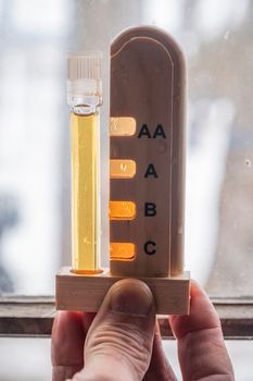 Close-up of maple syrup grading with test tube, showcasing light reflection in Québec.
