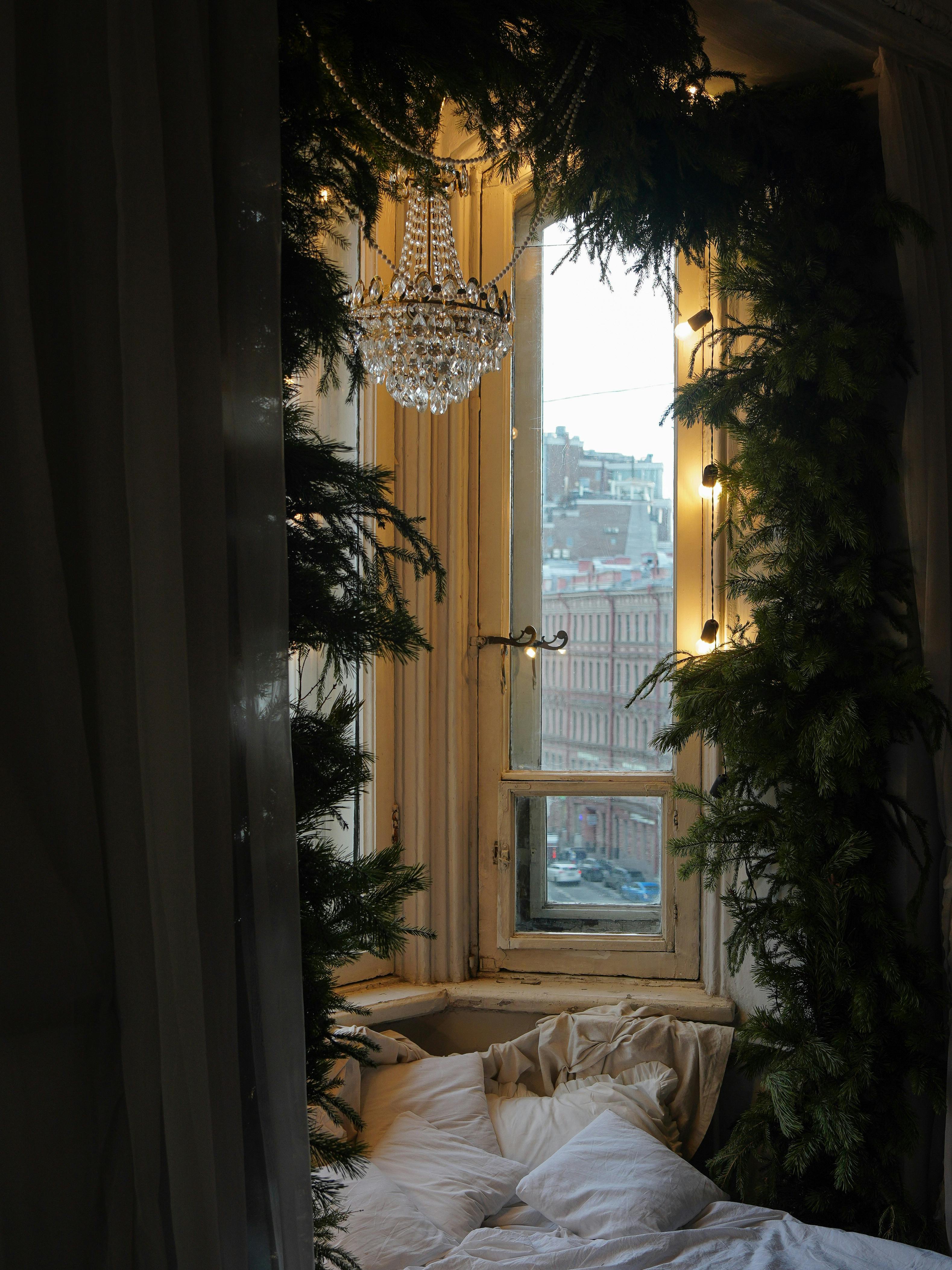 A serene window nook adorned with greenery and chandelier. Perfect for relaxing.