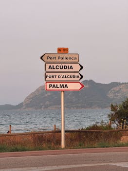 Signpost showing directions to major Mallorca locations with coastal view.