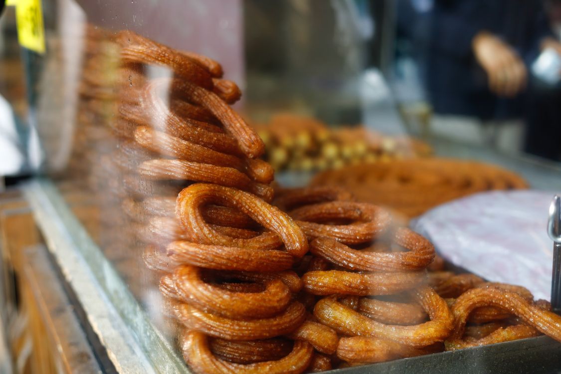 Free Golden churros stacked at a street food stall, showcasing festive treats. Stock Photo