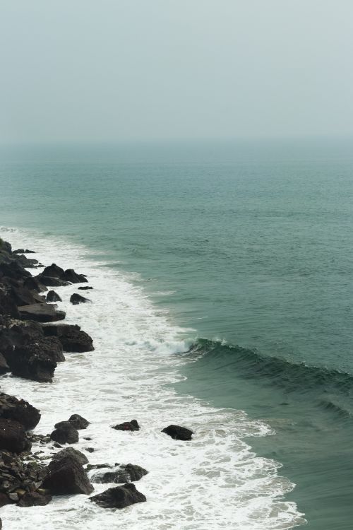 Free A breathtaking view of the ocean waves crashing against the rocky coast of Kerala, India. Stock Photo