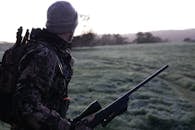 黎明时分，澳大利亚维多利亚州的猎人穿着迷彩服，用步枪勘察风景