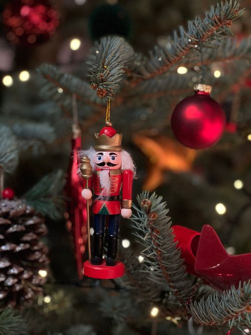 Free Nutcracker ornament hangs, adding charm to a festive Christmas tree with lights. Stock Photo