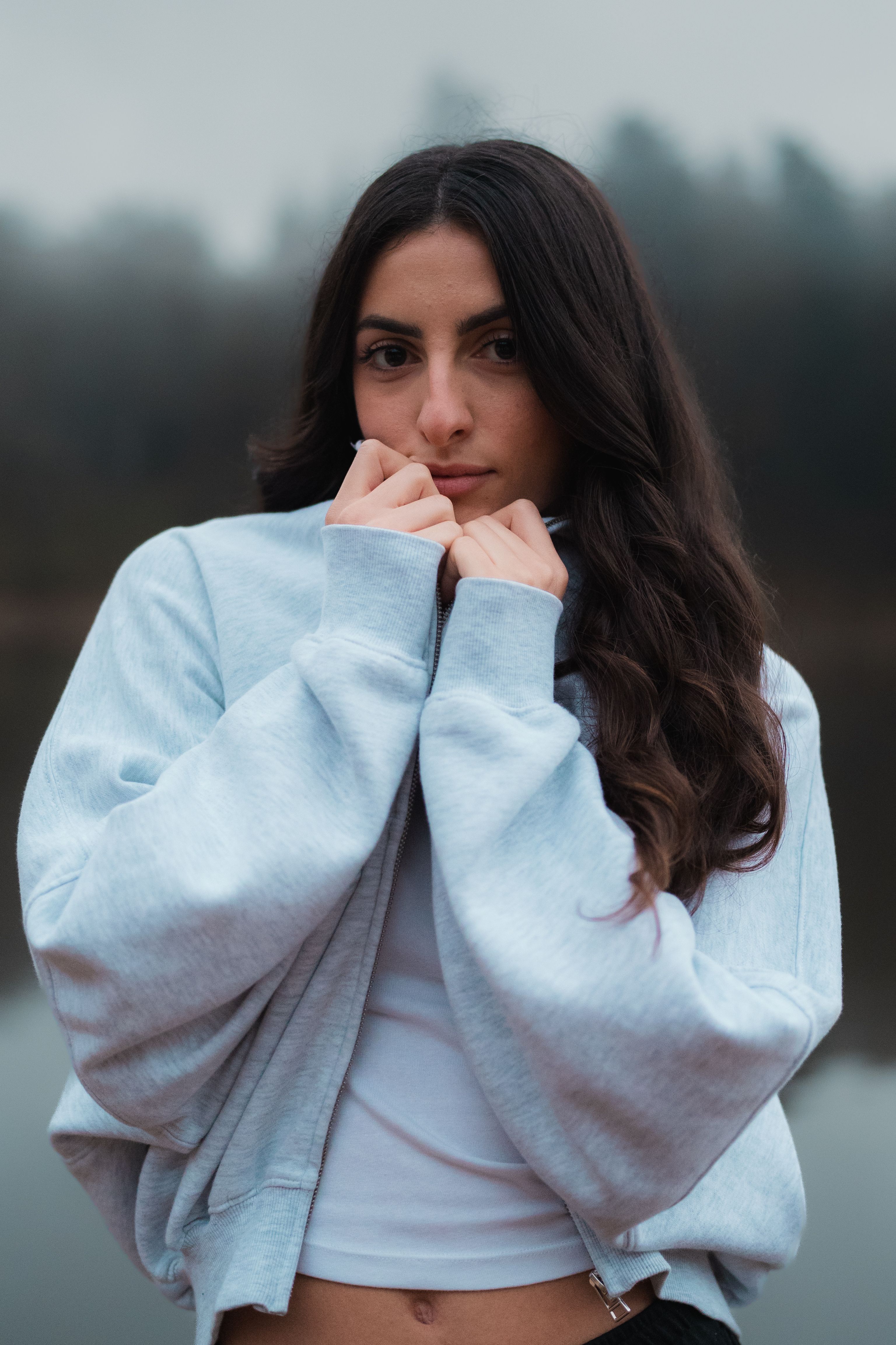 Portrait of a young woman in a sweatshirt by a misty lake. Casual and contemplative mood.